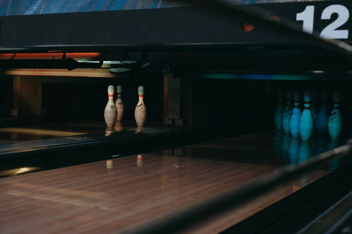 A dimly lit bowling alley showcasing lined-up pins ready for a strike.